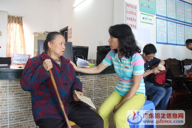 66歲的殘疾老黨員鄧美群（低保戶）接過余若丹副校長給的慰問金
